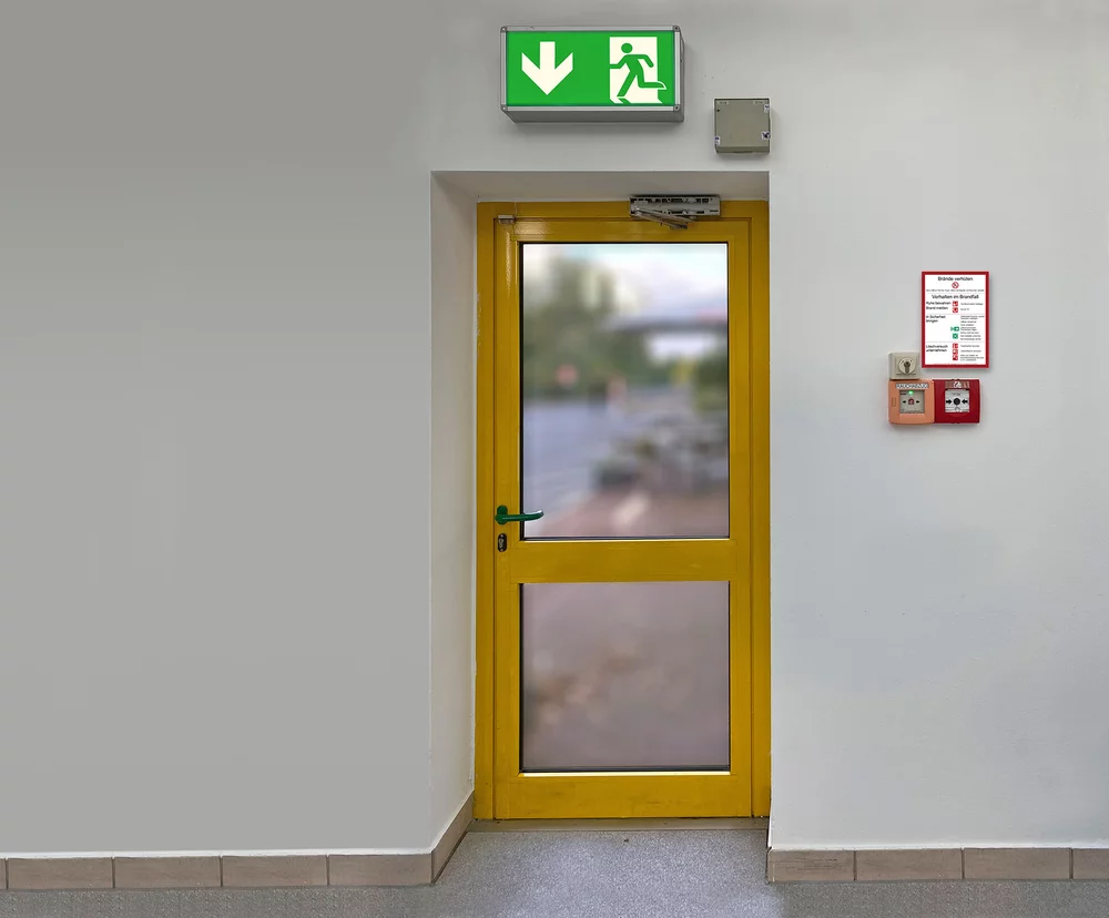 Brandschutzordnung Teil A, Rauch- und Handfeuermelder neben Notausgang